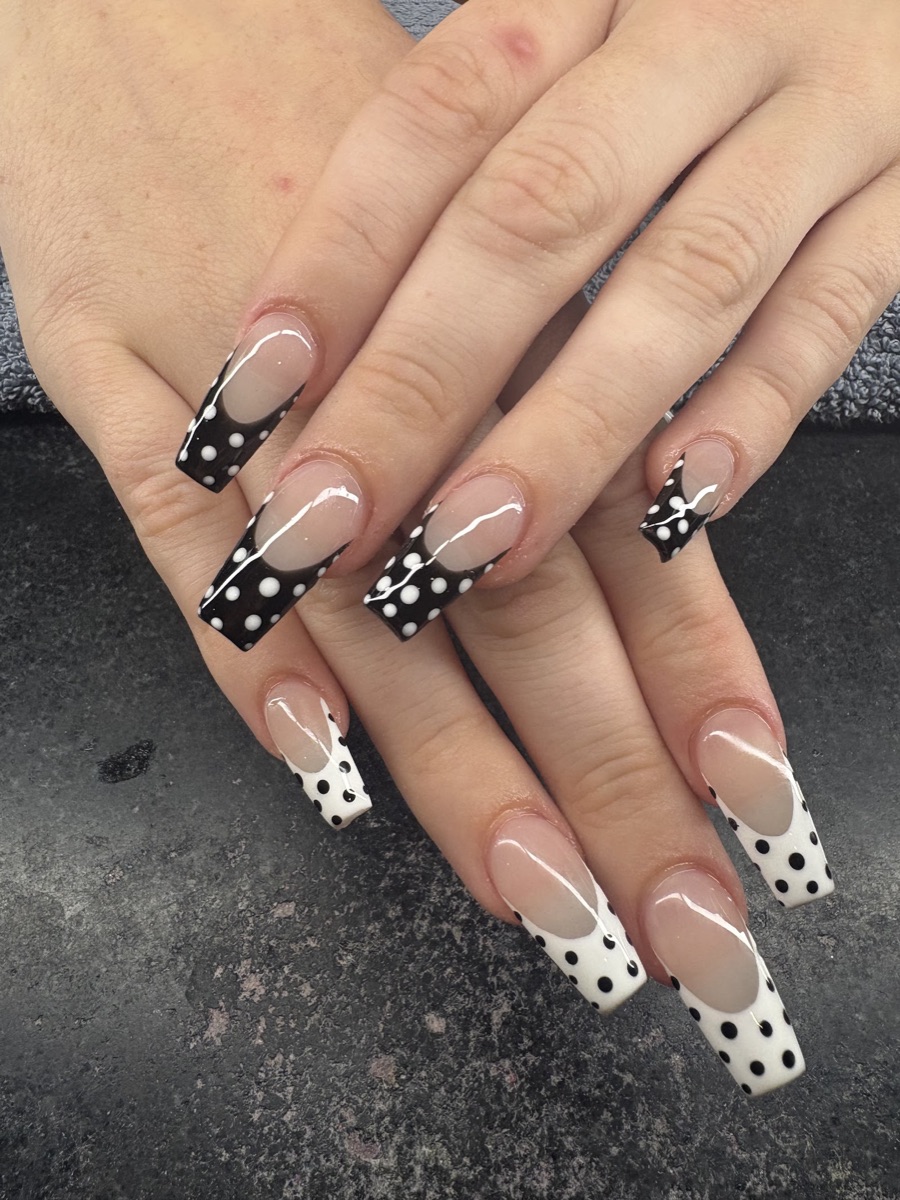 Long coffin nails with black and white French tips and polka dots.